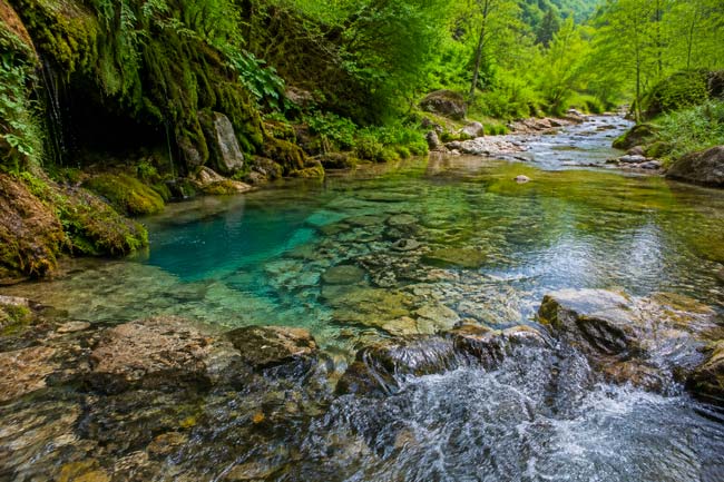 Manantial de aguas subterráneas alimentando un río de montaña de aguas cristalinas