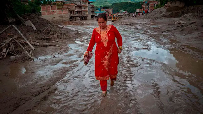 mujer local caminando por la zona devastada de la riada de Nepal y Tibet